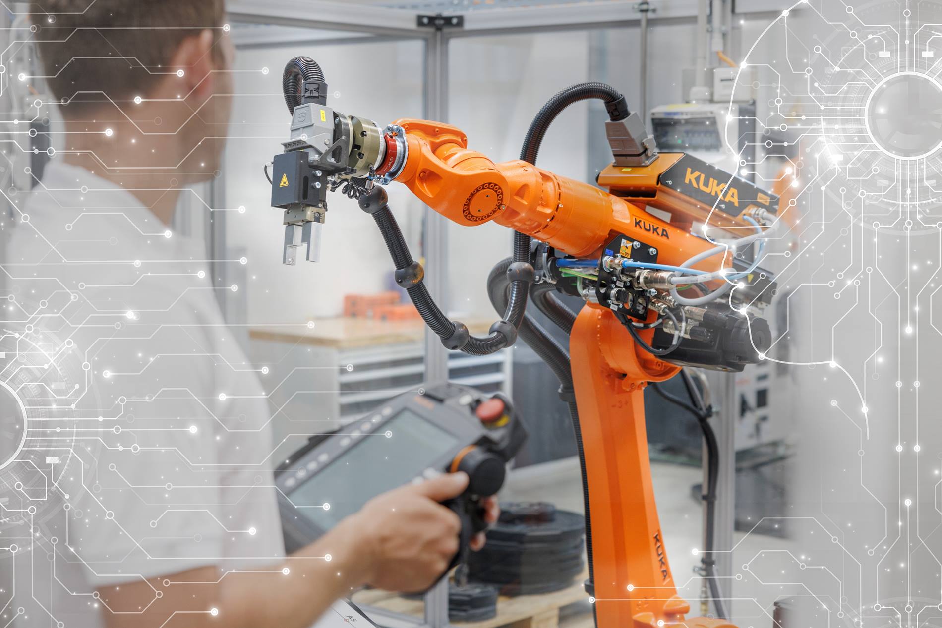 An orange KUKA industrial robot arm operates in a modern production environment, monitored by a person with a control unit, with technical circuits and digital connections in the background illustrating the integration of artificial intelligence and automation in the industry.