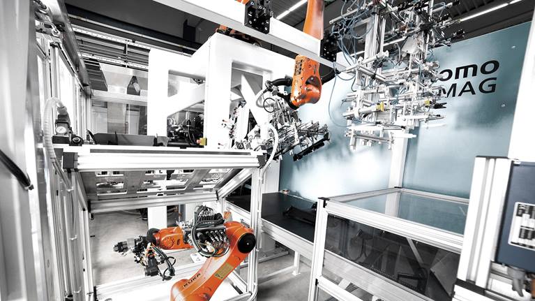 这些机器人在紧凑的工作单元中进行着协同工作。